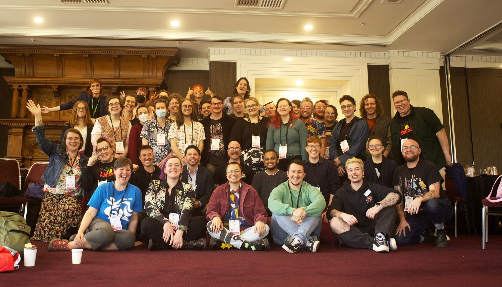 A group of 40-50 trans people posing for a photo together. They're all looking pretty happy.